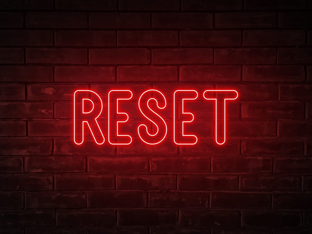 Reset - neon light word on brick wall background